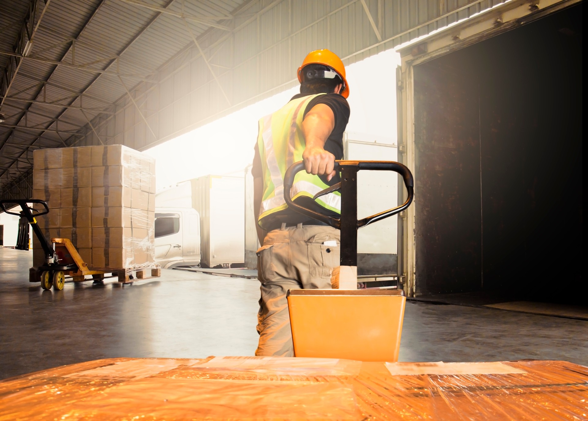 Warehouse worker unloading pallet shipment goods into a truck container